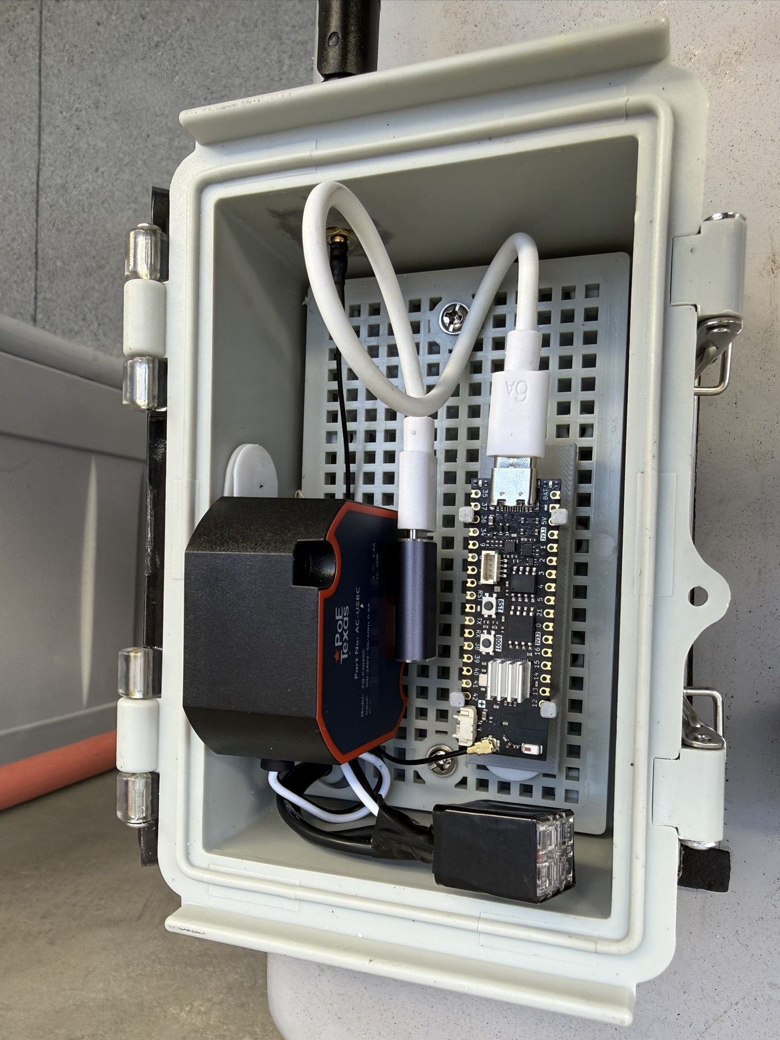 Inside the outdoor enclosure: the ProS3D board with its external antenna lead, beside the in-wall USB-C power supply